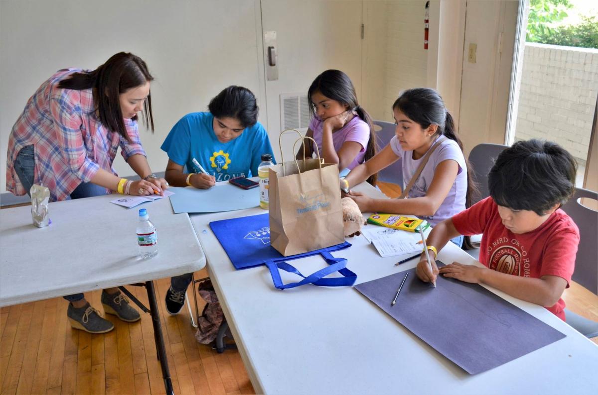 A volunteer assists children with a reading and drawing exercise