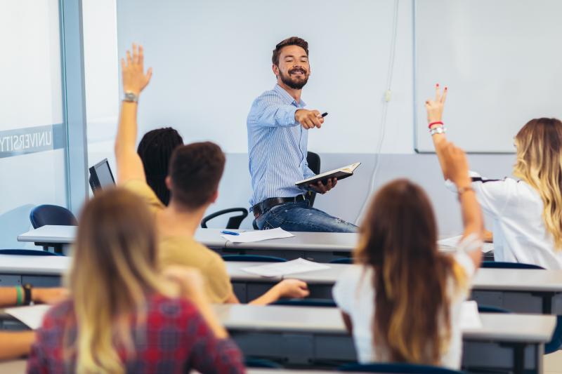 Teacher with students raising their hands in a classroom